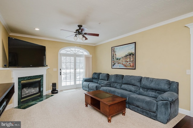 living room featuring a premium fireplace, ceiling fan, and crown molding