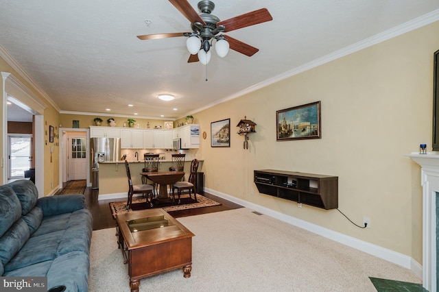 living room featuring a high end fireplace, ceiling fan, ornamental molding, and carpet floors