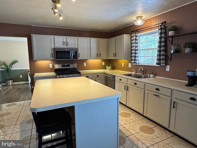 kitchen featuring appliances with stainless steel finishes, a kitchen island, white cabinets, a breakfast bar, and sink