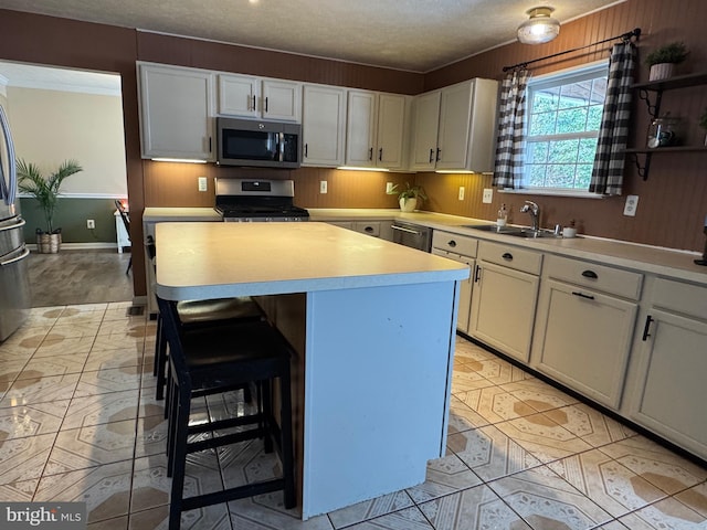 kitchen with a center island, a kitchen bar, sink, appliances with stainless steel finishes, and white cabinets