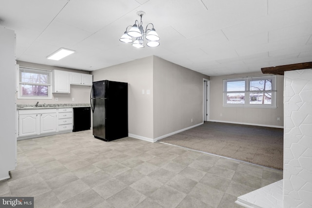 kitchen featuring white cabinetry, hanging light fixtures, a notable chandelier, light colored carpet, and black appliances