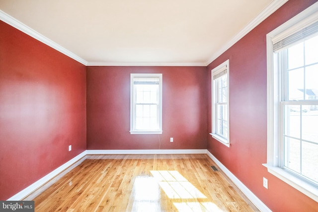 spare room with crown molding, a healthy amount of sunlight, and light wood-type flooring