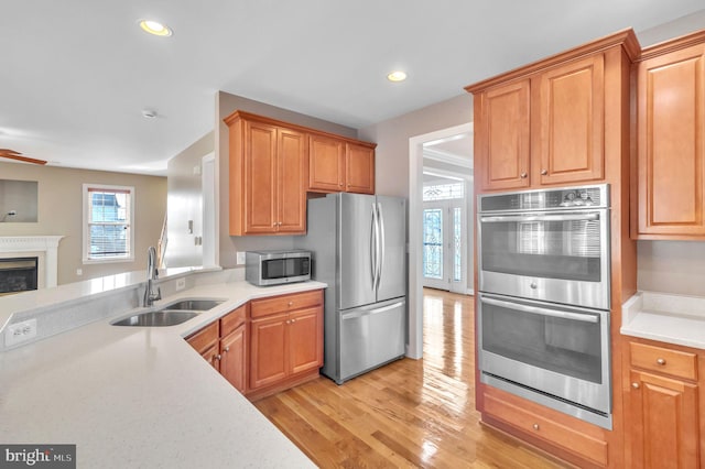 kitchen with stainless steel appliances, sink, and light hardwood / wood-style floors