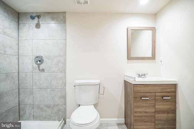 bathroom with tiled shower, vanity, and toilet