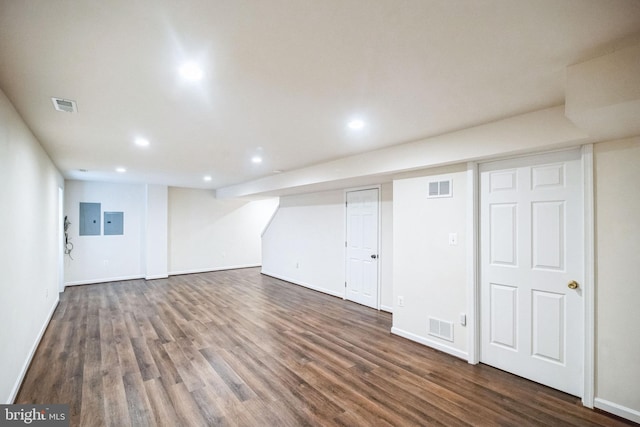 basement with dark hardwood / wood-style flooring and electric panel