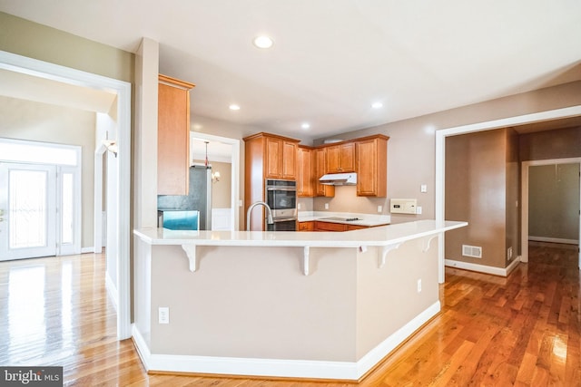 kitchen with black electric cooktop, a kitchen breakfast bar, kitchen peninsula, and stainless steel refrigerator