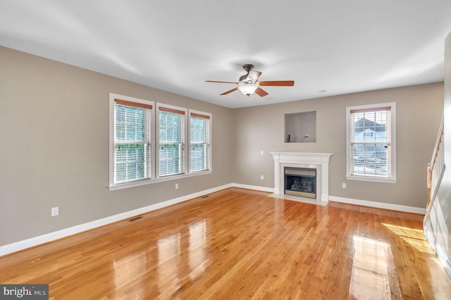 unfurnished living room with a wealth of natural light, ceiling fan, and light wood-type flooring