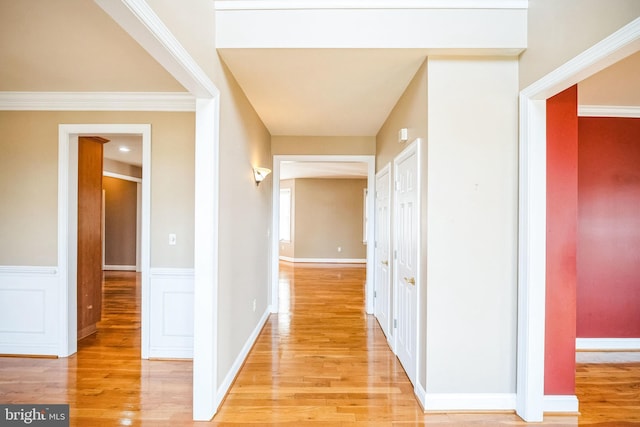 corridor with crown molding and light hardwood / wood-style floors