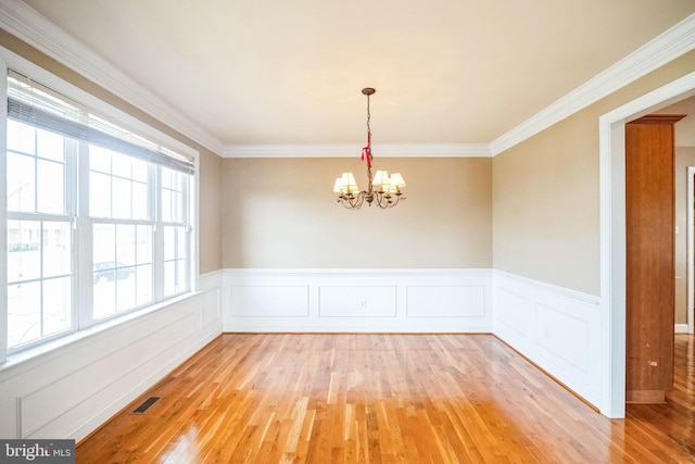 spare room with crown molding, light hardwood / wood-style flooring, and a notable chandelier