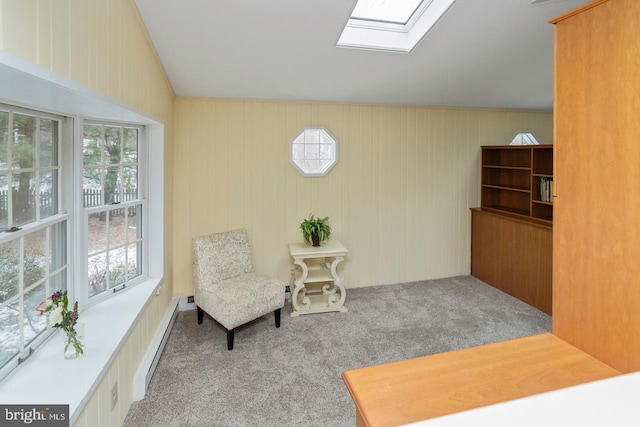 sitting room with a skylight, light colored carpet, wood walls, and a baseboard radiator