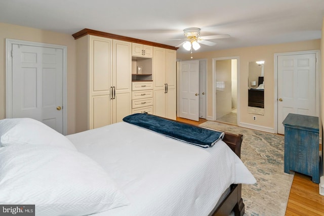 bedroom with ceiling fan, ensuite bathroom, and light wood-type flooring