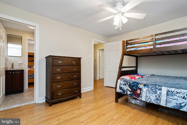 bedroom featuring ceiling fan, light hardwood / wood-style floors, sink, and ensuite bath