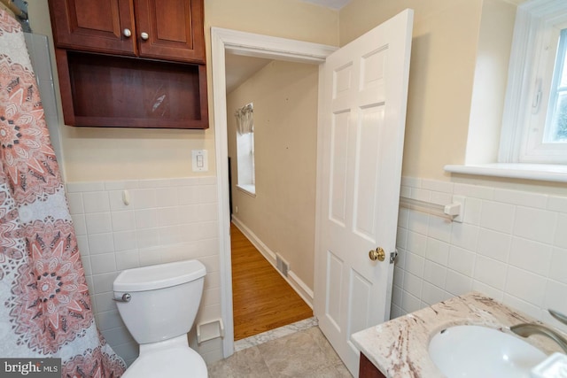 bathroom with toilet, tile walls, tile patterned floors, and vanity