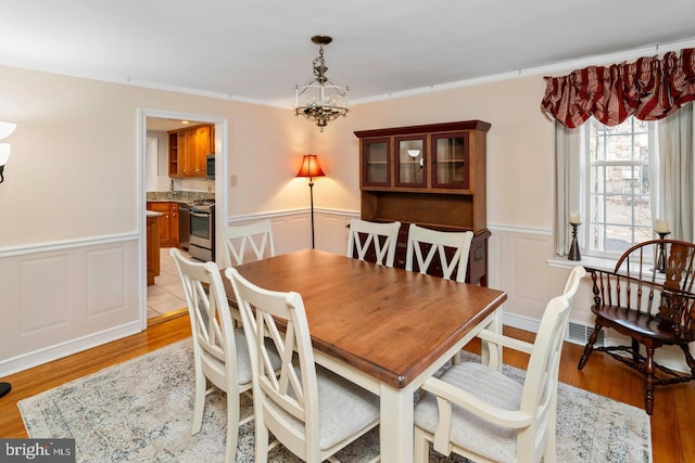 dining room featuring light hardwood / wood-style flooring and crown molding