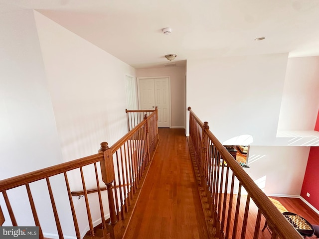 corridor featuring dark wood-style flooring, an upstairs landing, and baseboards