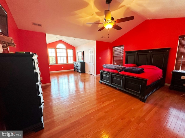 bedroom featuring light wood-style floors, visible vents, vaulted ceiling, and baseboards