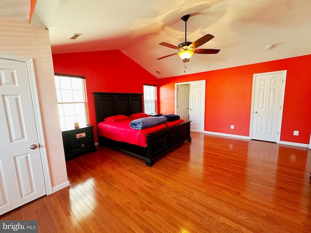 bedroom with visible vents, baseboards, a ceiling fan, lofted ceiling, and wood finished floors