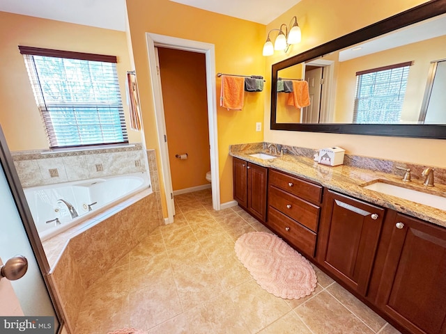 full bathroom featuring double vanity, a jetted tub, a sink, and toilet