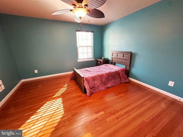 bedroom featuring light wood-style floors, visible vents, baseboards, and ceiling fan