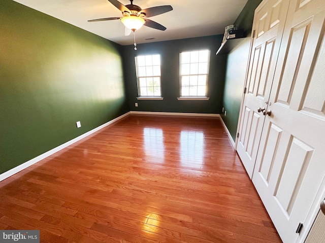 empty room featuring light wood finished floors, a ceiling fan, and baseboards