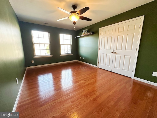 unfurnished bedroom with a closet, visible vents, baseboards, and wood finished floors