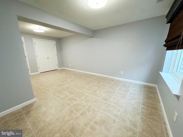 empty room with baseboards and light tile patterned floors