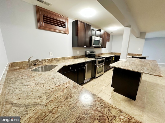 kitchen with dark brown cabinetry, visible vents, appliances with stainless steel finishes, a peninsula, and a sink