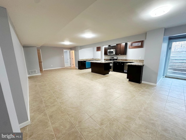 kitchen featuring visible vents, appliances with stainless steel finishes, open floor plan, a center island, and light countertops