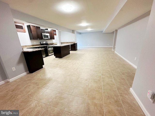 kitchen featuring appliances with stainless steel finishes, open floor plan, a center island, light countertops, and a kitchen bar