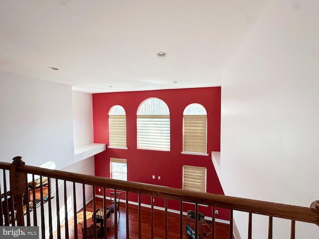 hall featuring an upstairs landing, baseboards, and wood finished floors