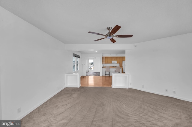 unfurnished living room featuring light colored carpet and ceiling fan