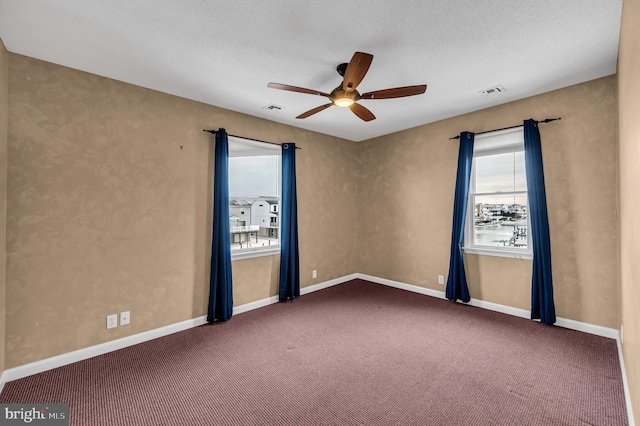 carpeted spare room featuring a textured ceiling and ceiling fan