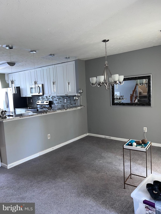 kitchen with pendant lighting, white cabinetry, stainless steel appliances, and decorative backsplash