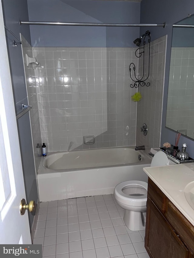 full bathroom with tile patterned flooring, tiled shower / bath, vanity, and toilet