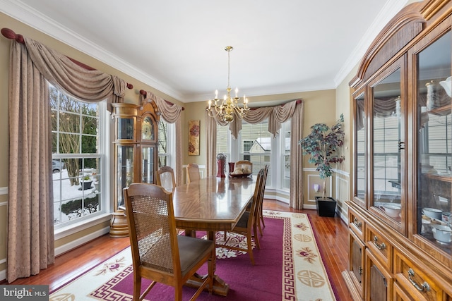 dining area with crown molding, light hardwood / wood-style flooring, and a notable chandelier