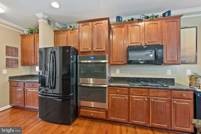 kitchen featuring black appliances, dark stone countertops, ornamental molding, and light hardwood / wood-style flooring