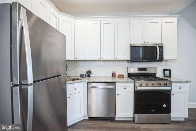 kitchen with appliances with stainless steel finishes, tasteful backsplash, white cabinetry, and light stone counters