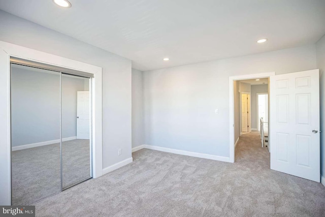 unfurnished bedroom featuring a closet and light colored carpet