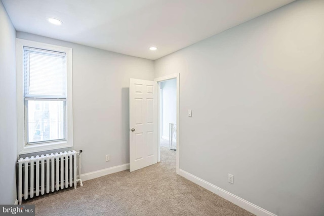 carpeted empty room featuring a wealth of natural light and radiator