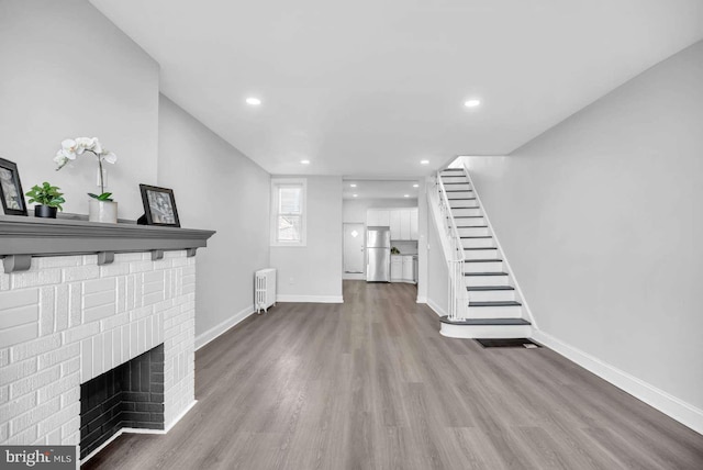 unfurnished living room featuring light hardwood / wood-style floors, a fireplace, and radiator