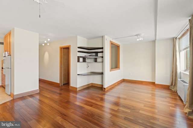 unfurnished living room featuring ceiling fan with notable chandelier, light hardwood / wood-style floors, and radiator heating unit