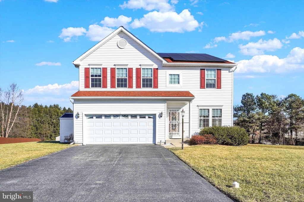 front of property featuring solar panels, a front yard, and a garage