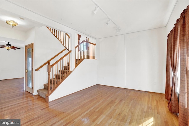 interior space featuring light wood-type flooring, rail lighting, and ceiling fan