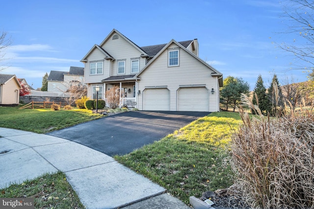 view of front of home featuring a front yard, covered porch, and a garage