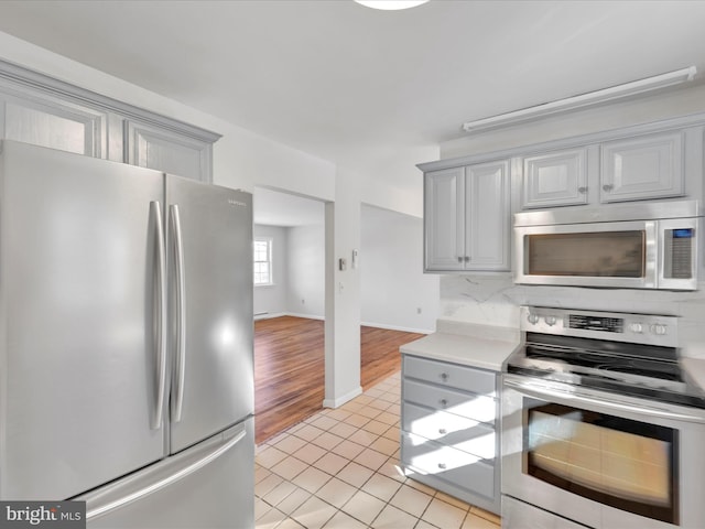 kitchen featuring tasteful backsplash, appliances with stainless steel finishes, light tile patterned flooring, and gray cabinetry