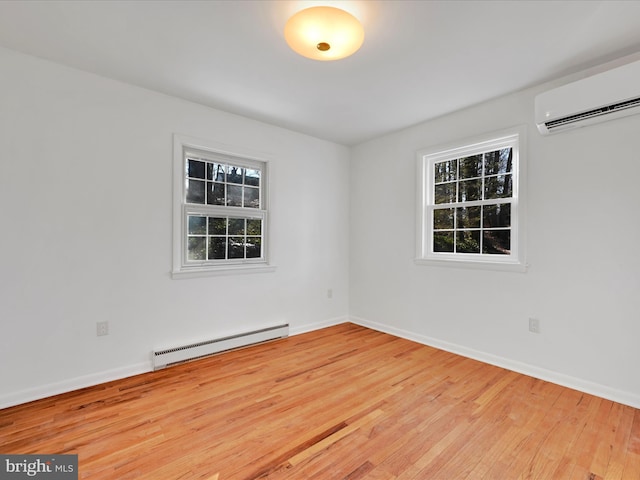 empty room featuring baseboard heating, light hardwood / wood-style floors, and a wall mounted air conditioner