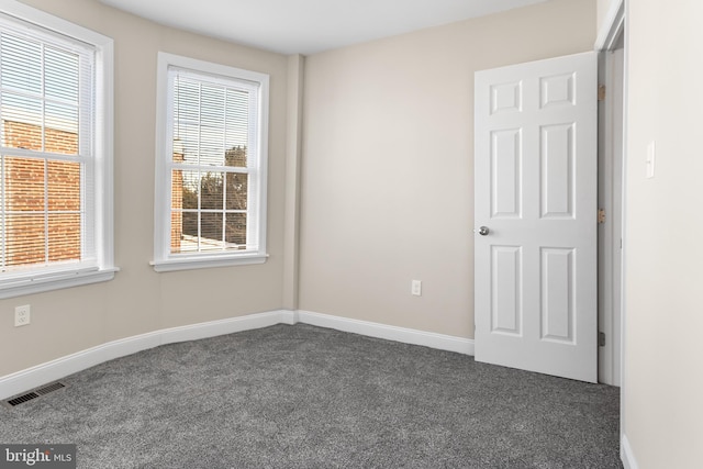 unfurnished room featuring dark carpet