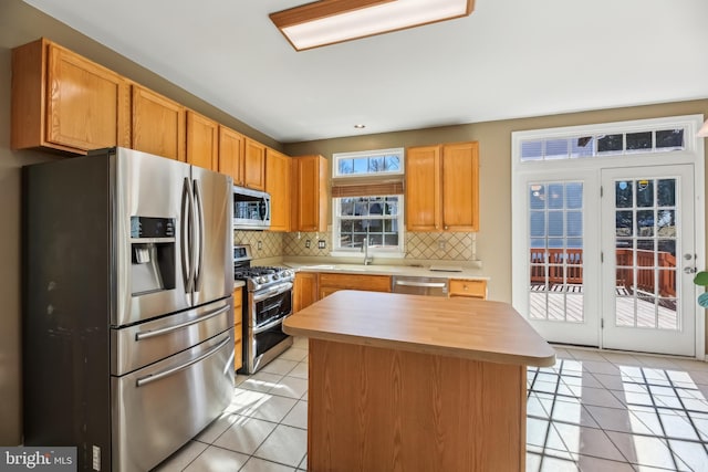 kitchen with appliances with stainless steel finishes, tasteful backsplash, light countertops, and light tile patterned floors