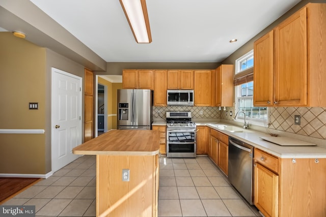 kitchen featuring light tile patterned floors, stainless steel appliances, a sink, and wooden counters