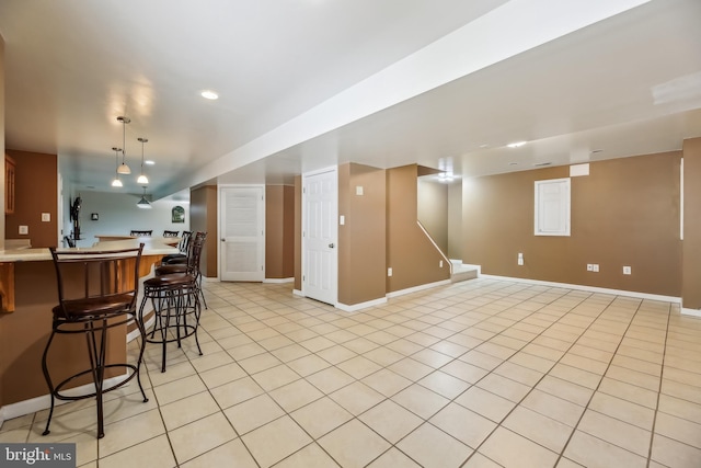 kitchen with baseboards, light countertops, a breakfast bar area, and light tile patterned floors